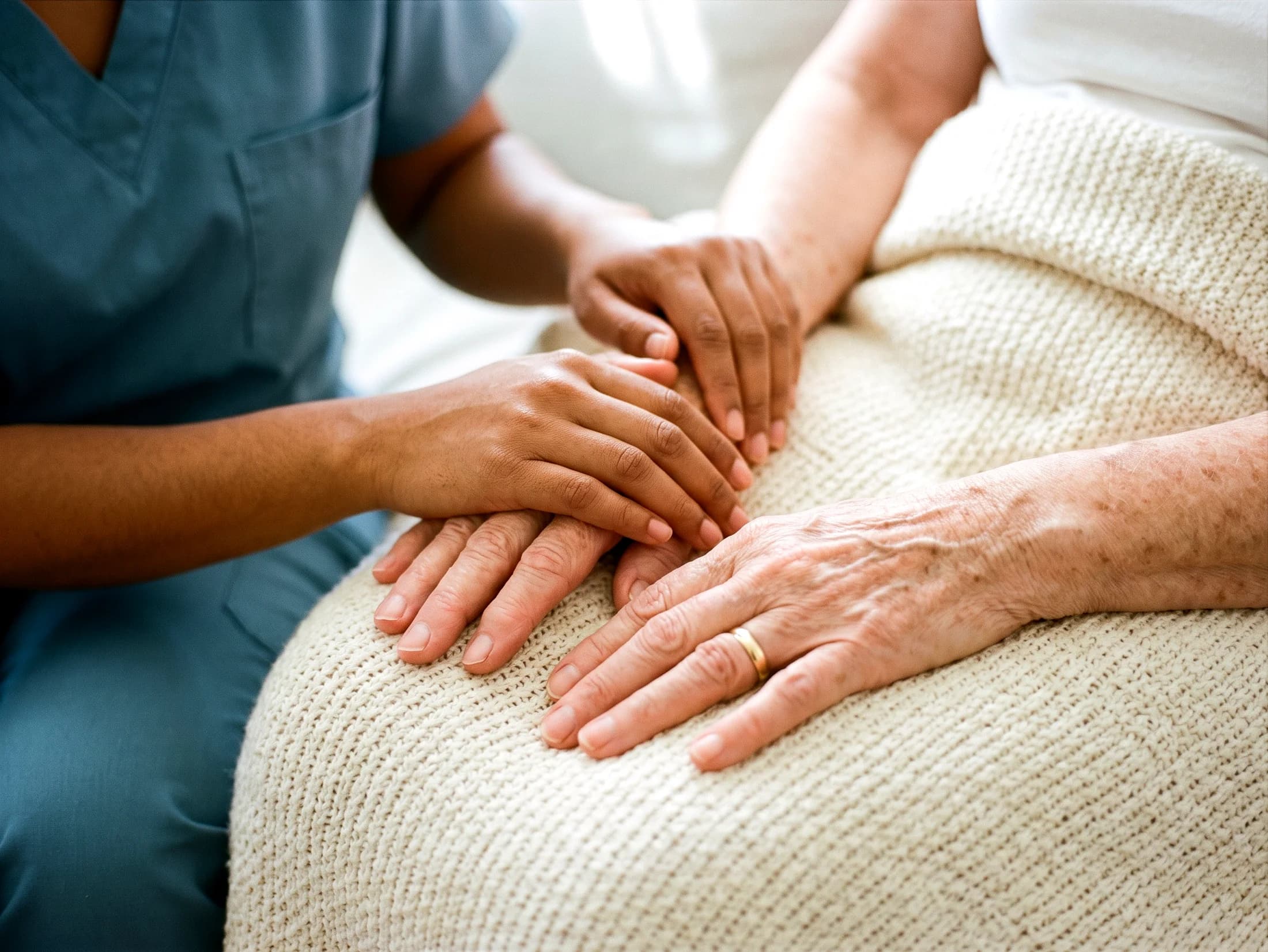 A caregiver's hands resting gently over a client's hands