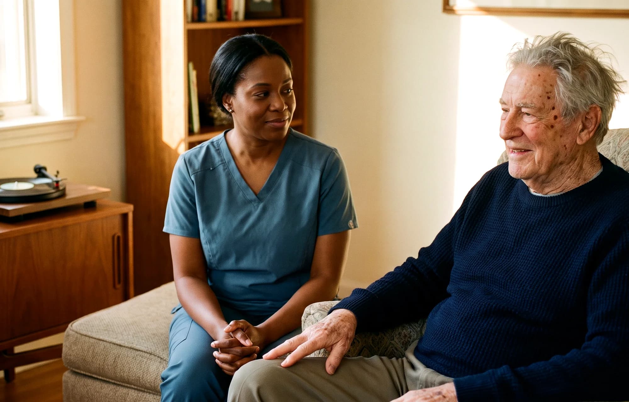 A caregiver sitting with an older man beside a record player and radio at home